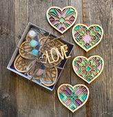Decorative heart-shaped wooden ornaments with stained glass patterns on a wooden surface.