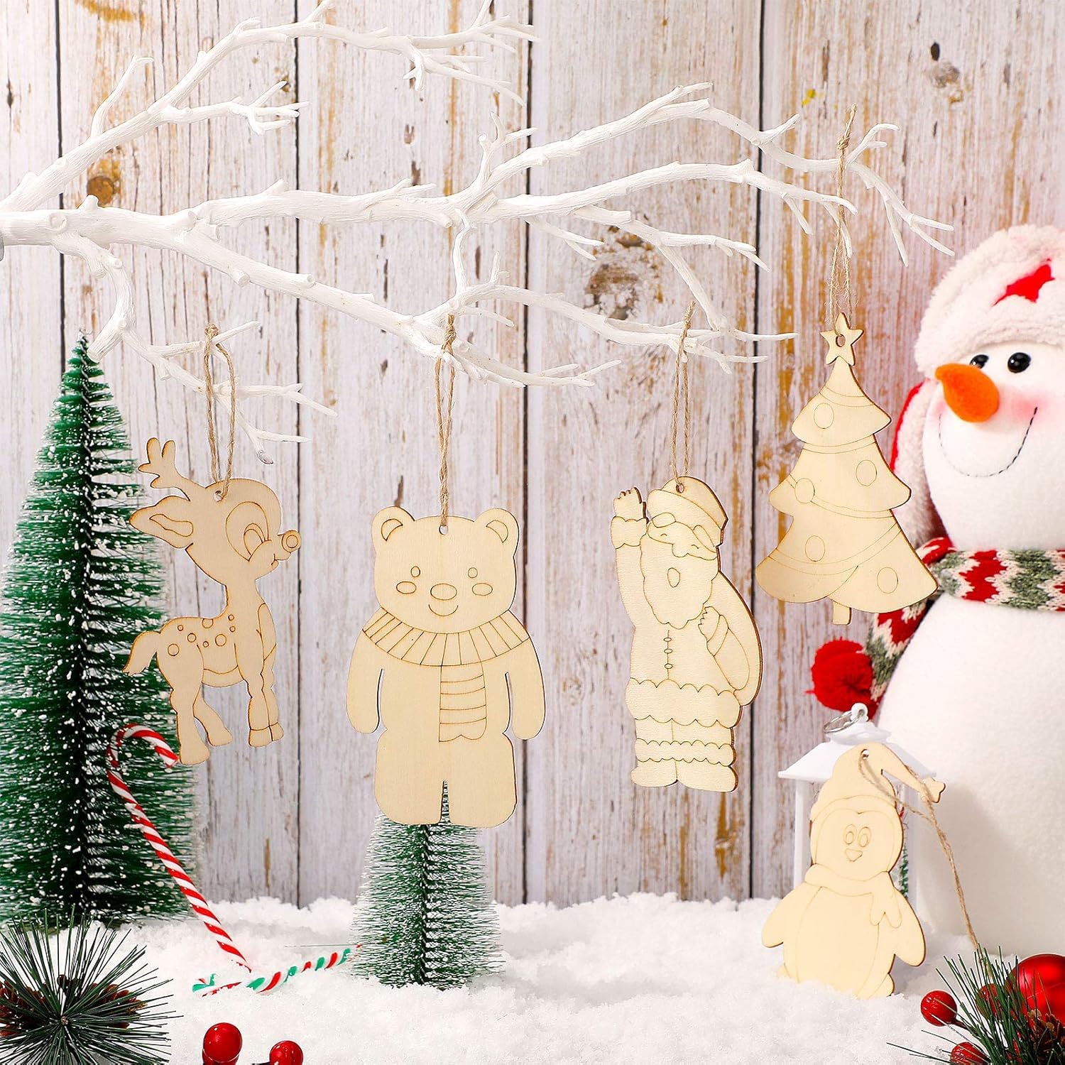 Wooden Christmas ornaments shaped like a reindeer, bear, and other animals with a snowman and trees in the background.