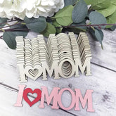 Wooden 'I LOVE MOM' letters on a wooden surface with flowers in the background