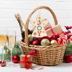 Christmas gift basket with champagne, ornaments, and a 'JOY' sign on a white background