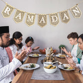 Family gathered around a dining table with 'RAMADAN' banner above, engaging in a meal.