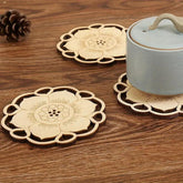 Decorative wooden coasters with floral designs on a wooden surface with a teapot.