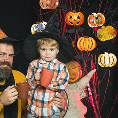 Two people in Halloween costumes with pumpkins and witch hats in the background.