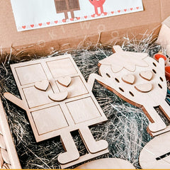 Wooden puzzle pieces shaped like a house and hearts on a box with packaging materials.