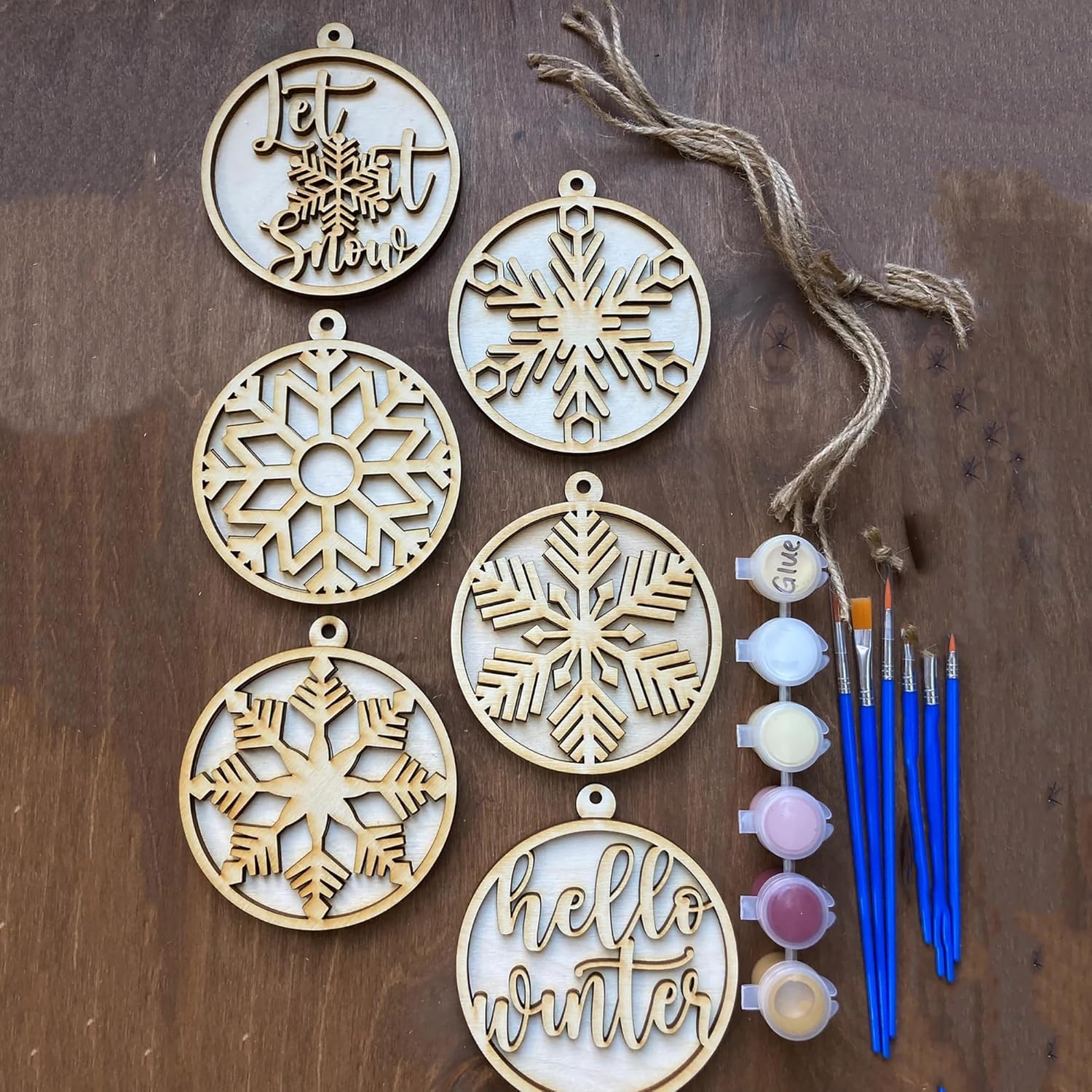 Wooden snowflake ornaments with paint supplies on a wooden surface