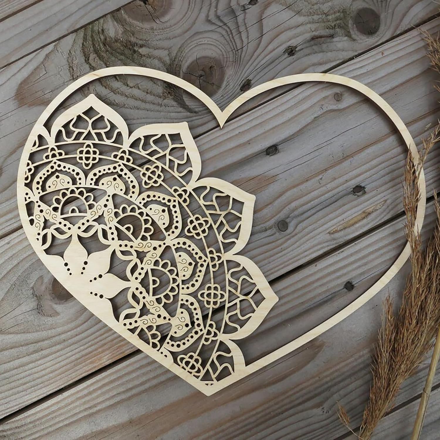 Decorative wooden heart with intricate cut-out patterns on a wooden surface.