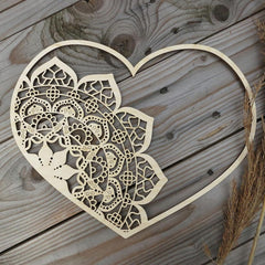 Decorative wooden heart with intricate cut-out patterns on a wooden surface.