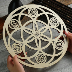 Decorative circular object with geometric patterns held by hands on a wooden surface