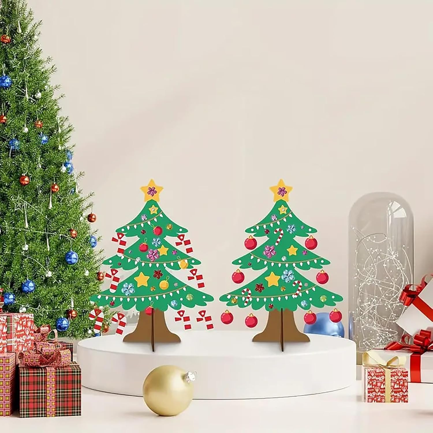 Decorative Christmas trees on a cake with a real Christmas tree and presents in the background.