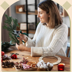 Woman arranging greenery on a wooden table with festive decorations.