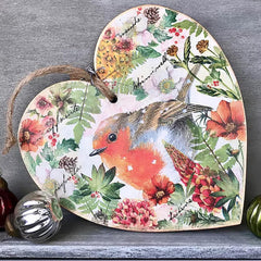 Decorative heart-shaped sign with a robin and floral design on a gray surface.