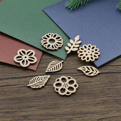 Decorative wooden flower and leaf shapes on a wooden surface with colored paper underneath.