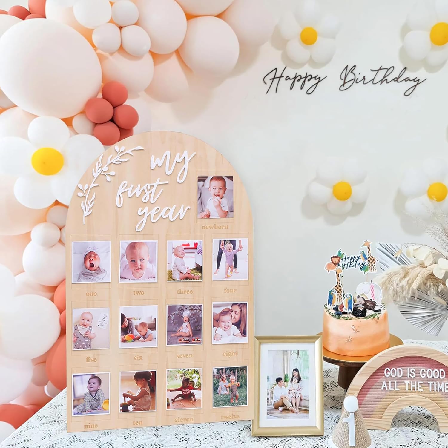 Wooden milestone board with baby photos, balloons, and a cake with 'Happy Birthday' text.