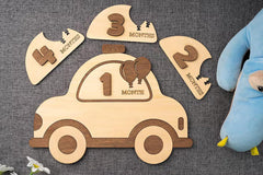 Wooden baby milestone car with detachable months displayed on a textured surface.