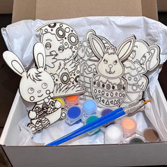 Box with wooden cutouts of rabbits and chicks, paint bottles, and brushes for painting.