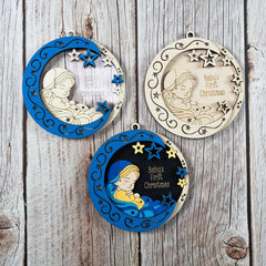 Three decorative ornaments featuring a baby and stars on a wooden surface.