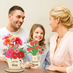 Family with decorative flowers and 'I love you Mom' signs on a table.