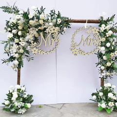 Decorative arch with floral arrangements and 'Mr' and 'Mrs' signs on a white background