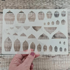 Decorative stencil held by a hand on a wooden surface