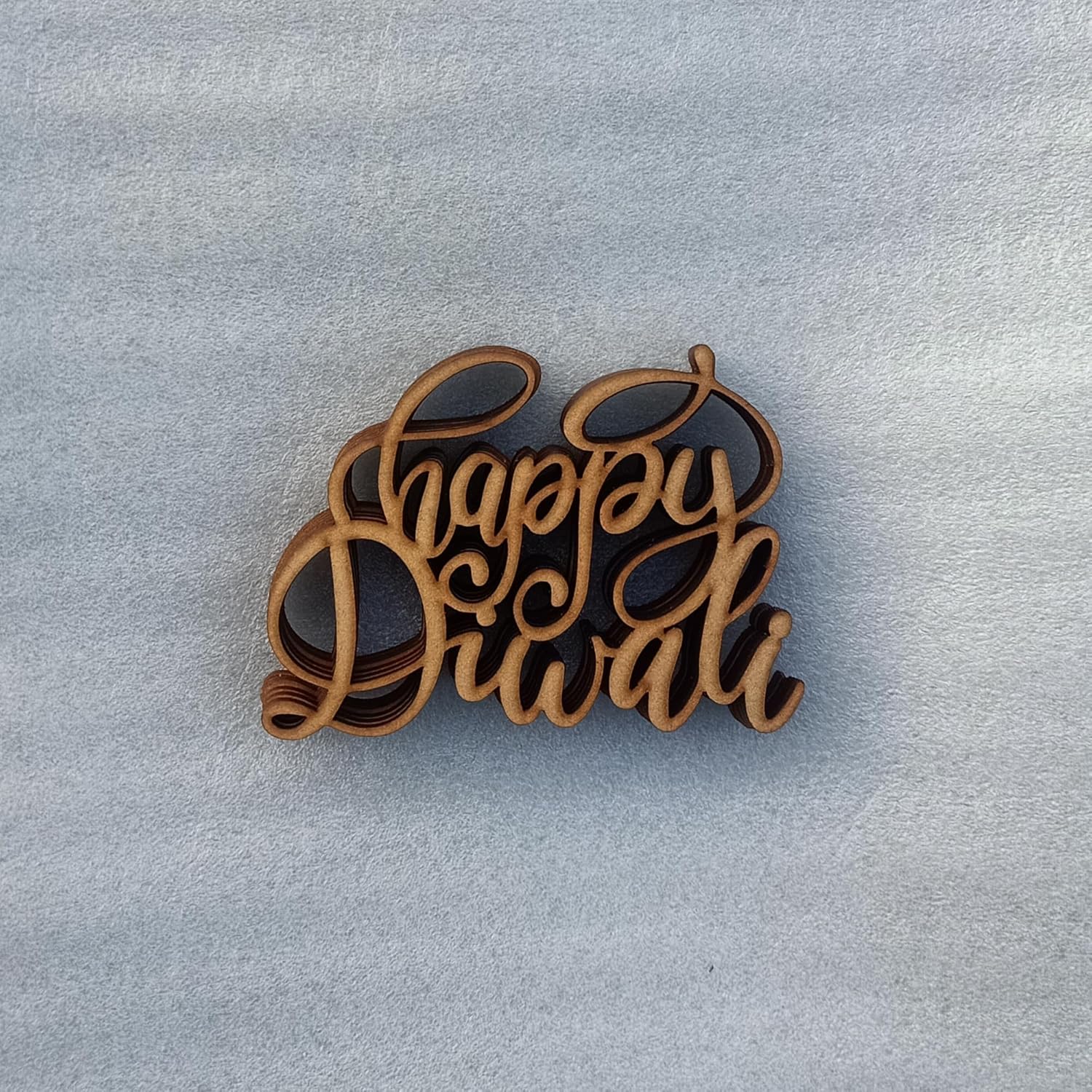 Wooden decorative piece with 'Happy Diwali' text on a light gray background