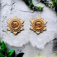 Two wooden decorative items with engraved designs on a textured surface with green leaves.