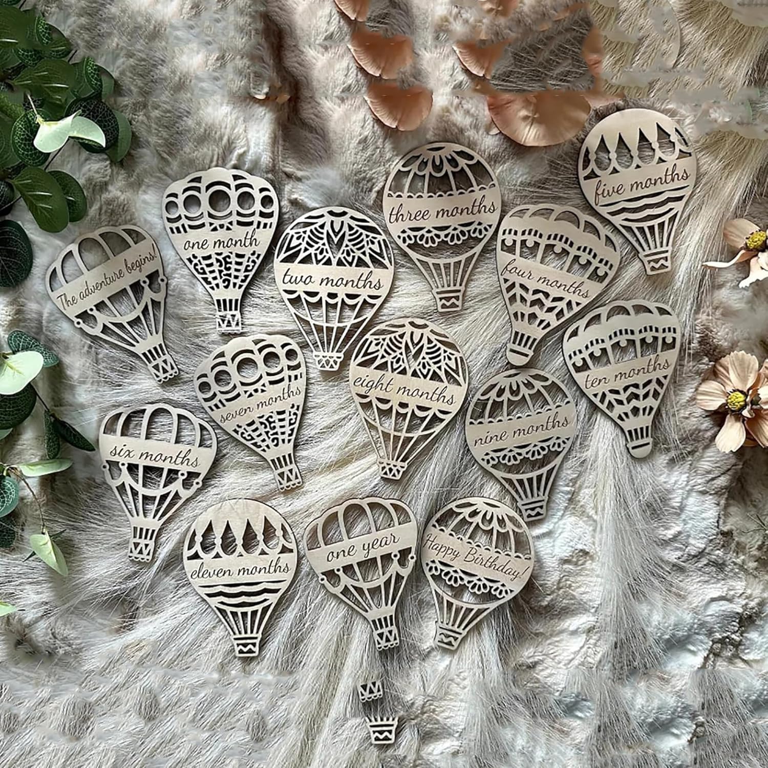 Wooden hot air balloon-shaped milestones with milestone numbers on a textured surface.