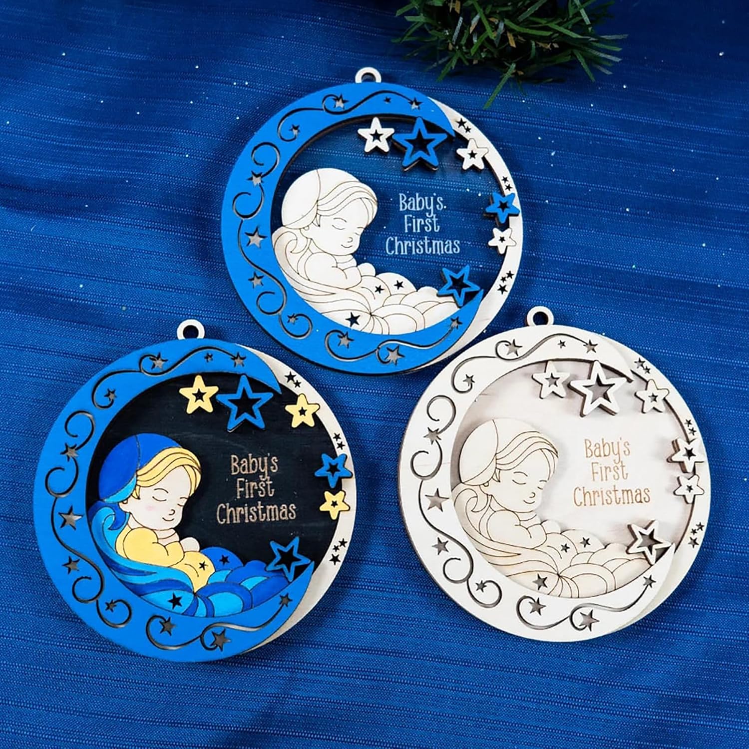 Three 'Baby's First Christmas' ornaments on a blue background