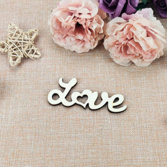 Wooden 'love' sign with pink flowers and a butterfly on a textured surface