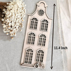 Decorative wooden cutout with window design and bicycle illustration on a textured surface with white flowers.