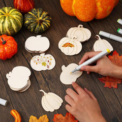 Wooden pumpkin-shaped cutouts with markers on a wooden surface with pumpkins and leaves.