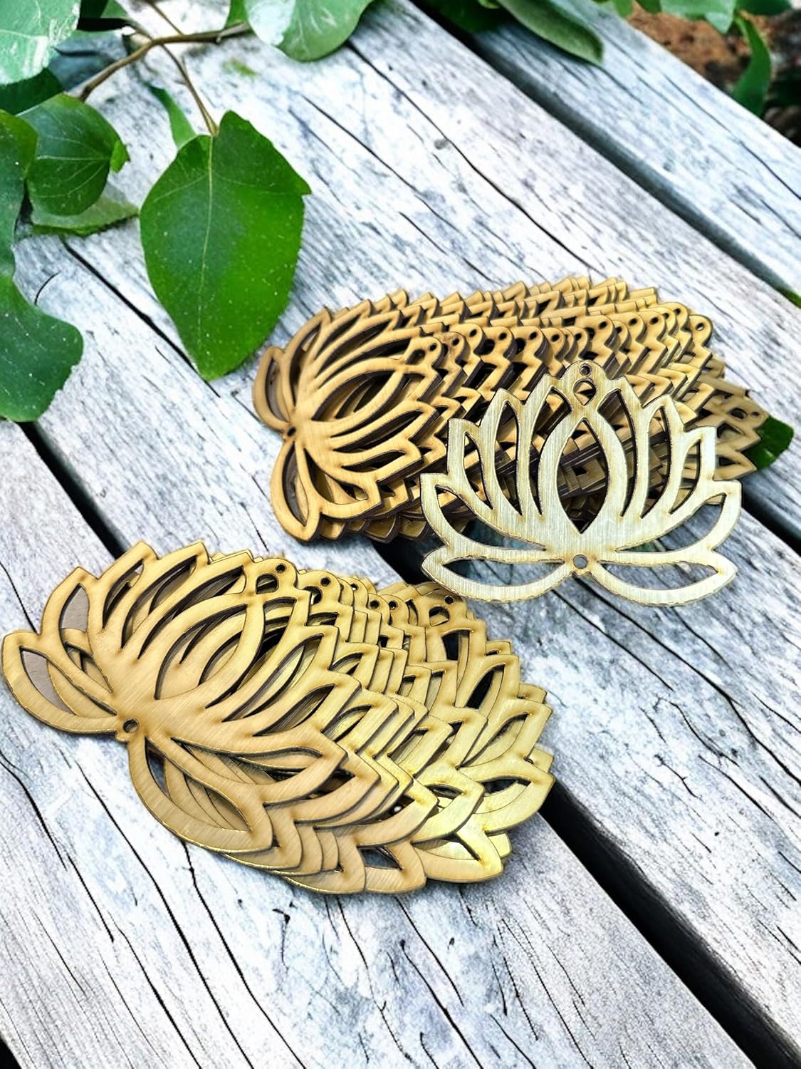 Three leaf-shaped coasters on a wooden surface with green leaves in the background