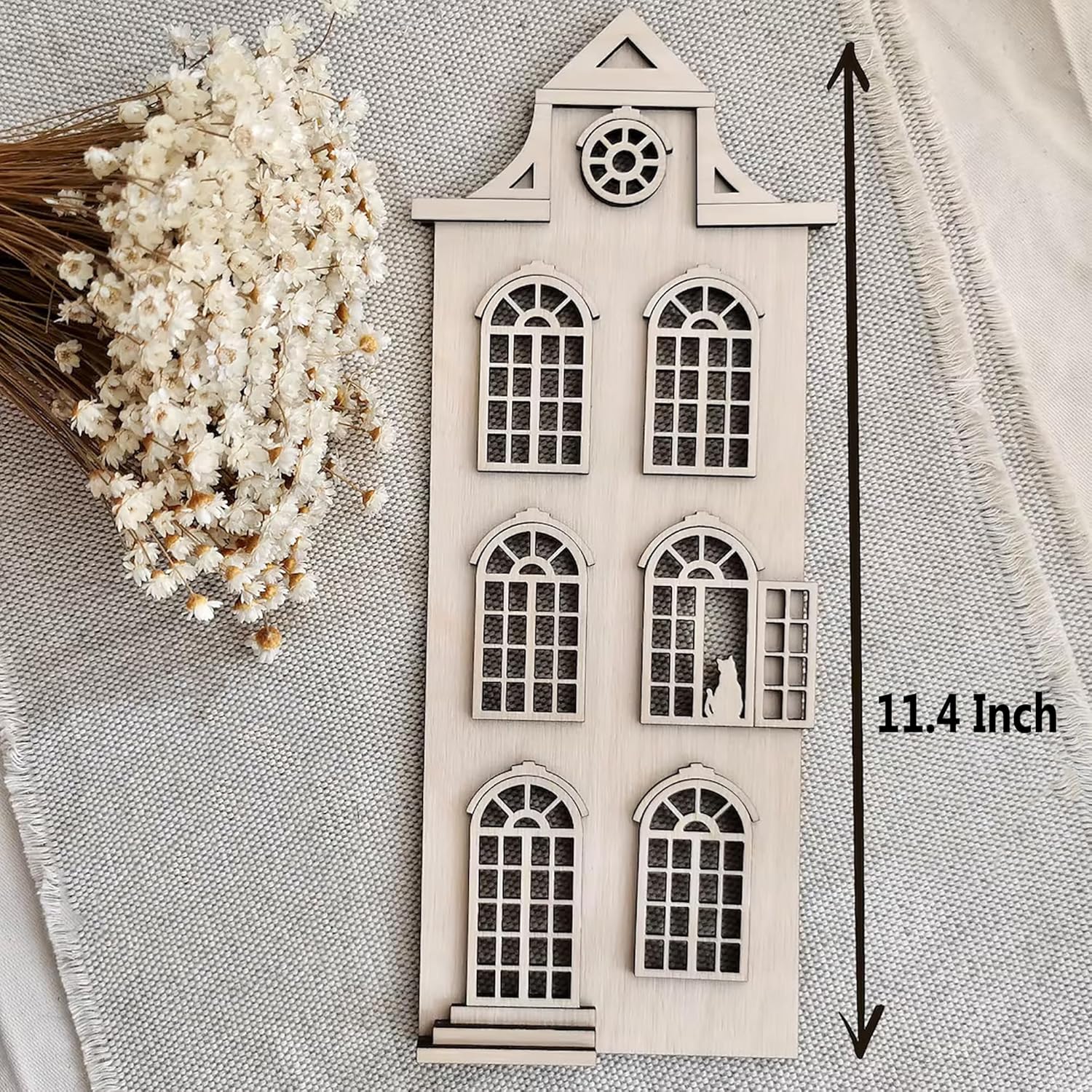 Small architectural model of a house with decorative elements on a textured fabric background