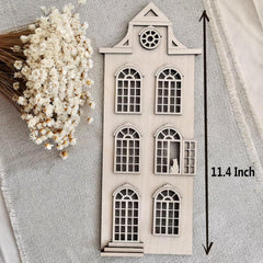 Small architectural model of a house with decorative elements on a textured fabric background