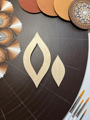Wooden earring shapes on a dark surface with color swatches and paintbrushes.