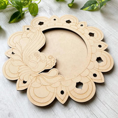 Decorative wooden wreath on a light surface with green leaves in the background