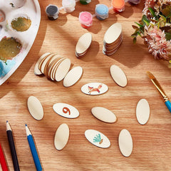 Wooden oval shapes with painted designs on a wooden table with art supplies.