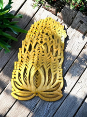 Decorative wooden pineapple on a wooden surface with plants in the background