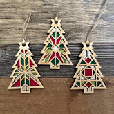 Three geometric Christmas tree ornaments on a wooden surface