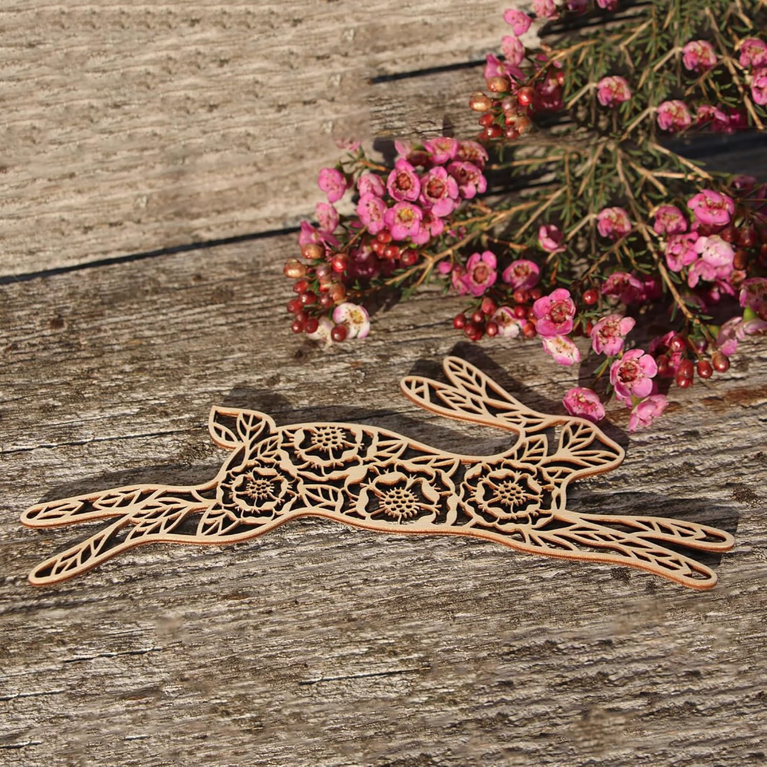 Decorative wooden hare on a wooden surface with pink flowers.