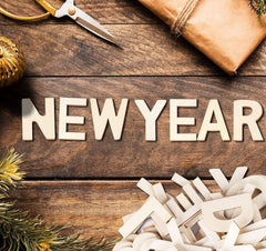 Wooden letters spelling 'NEW YEAR' on a rustic wooden surface with decorative items.
