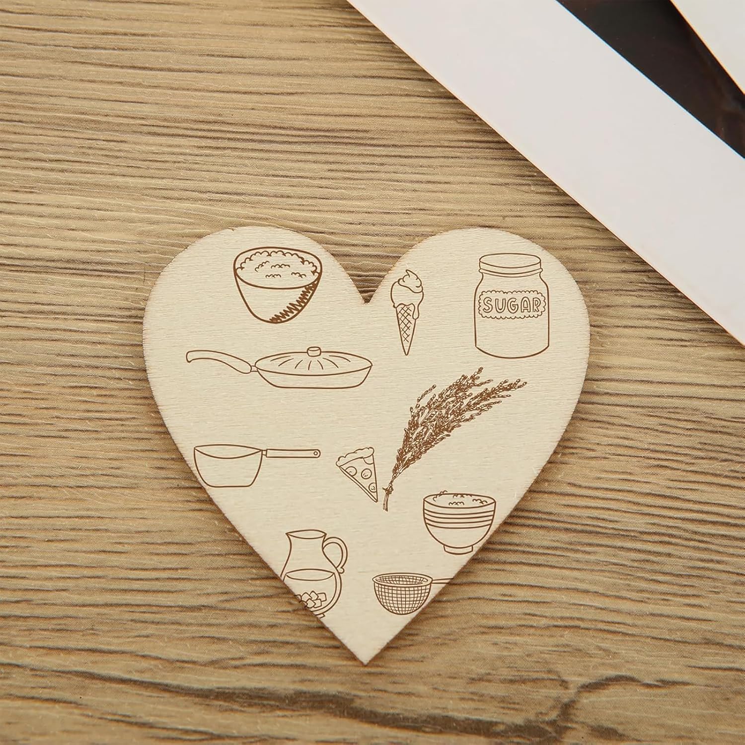 Heart-shaped wooden coaster with various illustrations on a wooden surface