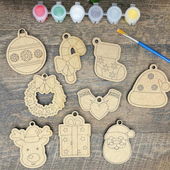 Wooden Christmas ornaments with paint containers and a brush on a wooden surface
