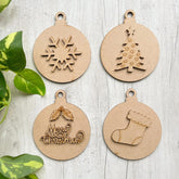 Four wooden Christmas ornaments with snowflake, tree, stocking, and 'Merry Christmas' designs on a light wooden surface.