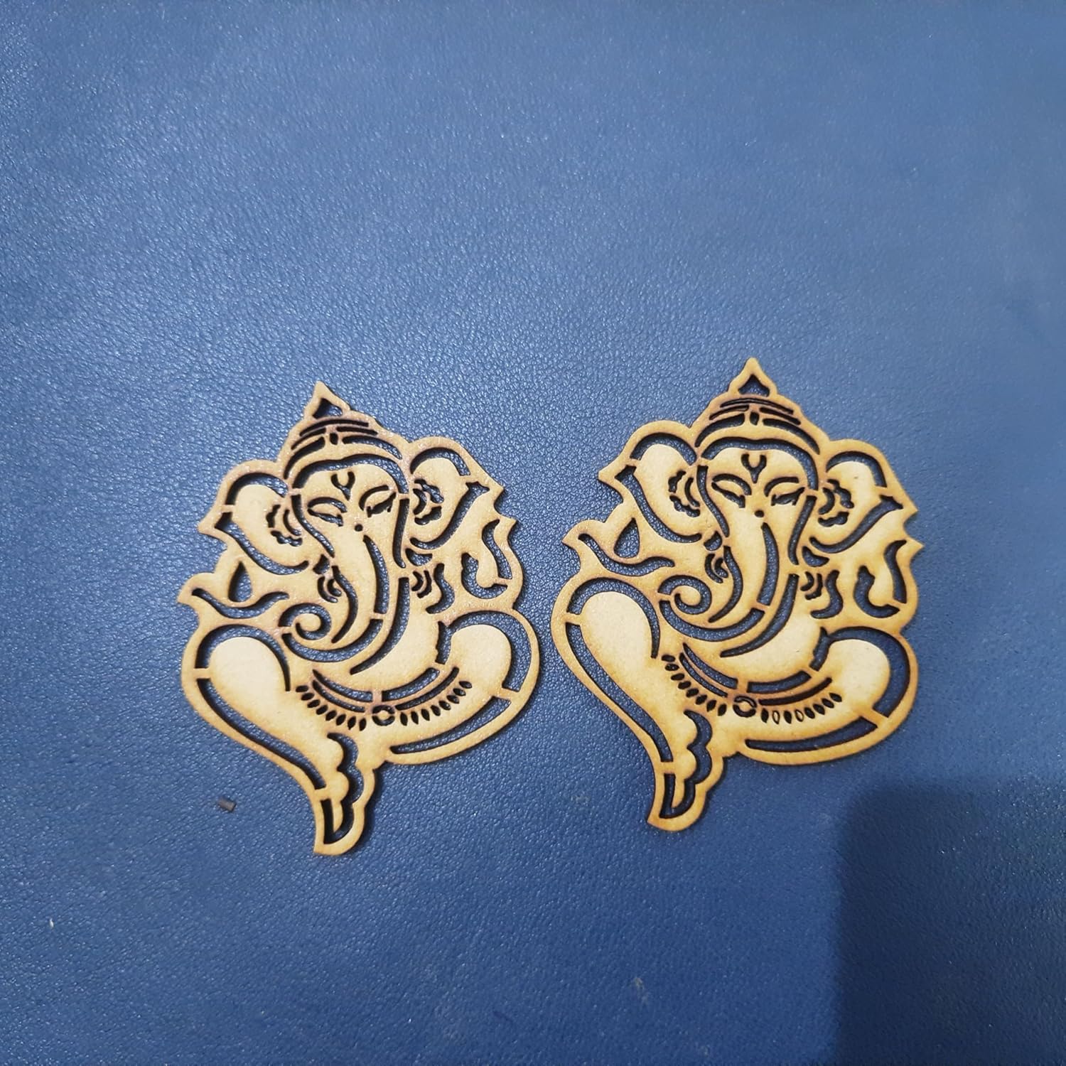 Two gold Ganesh cutouts on a blue background