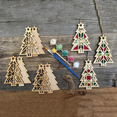 Wooden Christmas tree ornaments with paint supplies on a wooden surface