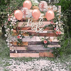 Decorative setup with 'Bride to Be' sign, balloons, and flowers on a wooden pallet.
