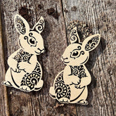 Two decorative rabbit figures with intricate patterns on a wooden surface