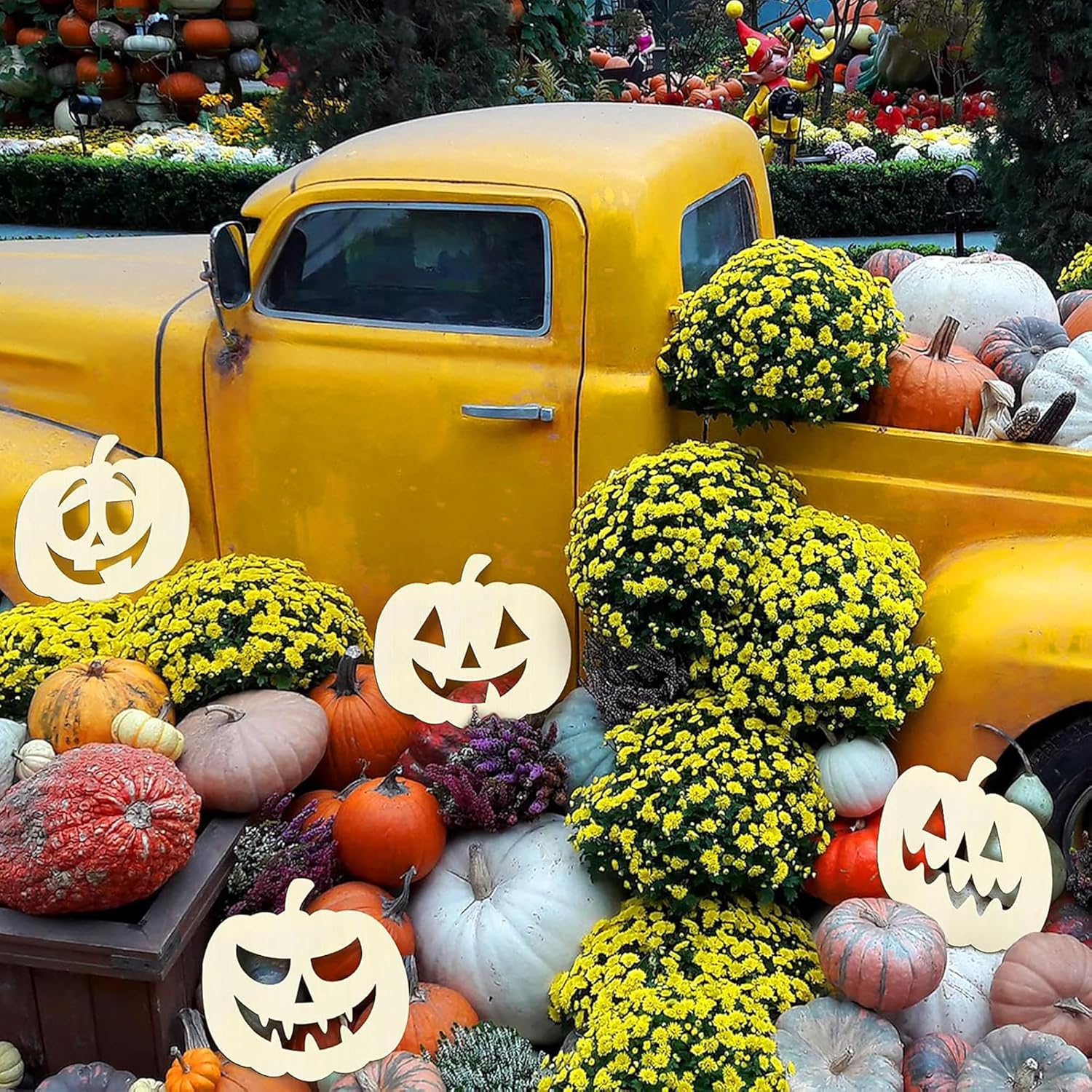 Vintage yellow truck decorated with pumpkins, flowers, and Halloween decorations in a festive setting.