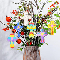 Decorative cross ornaments hanging from a branch with flowers and fruits.
