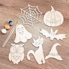 Halloween-themed wooden cutouts including a ghost, spider web, pumpkin, bat, cat, owl, and witch hat on a wooden surface with paint and brushes.